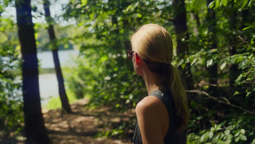 Athletic woman looking at lake through the trees