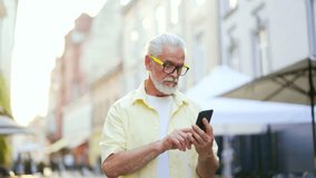 Senior stylish gray haired bearded man walking city street browsing mobile phone online map application looking around enjoying urban view Mature old male tourist with smartphone goes outside outdoors - Powered by Shutterstock - Get 15% off with code: PIKWIZARD15