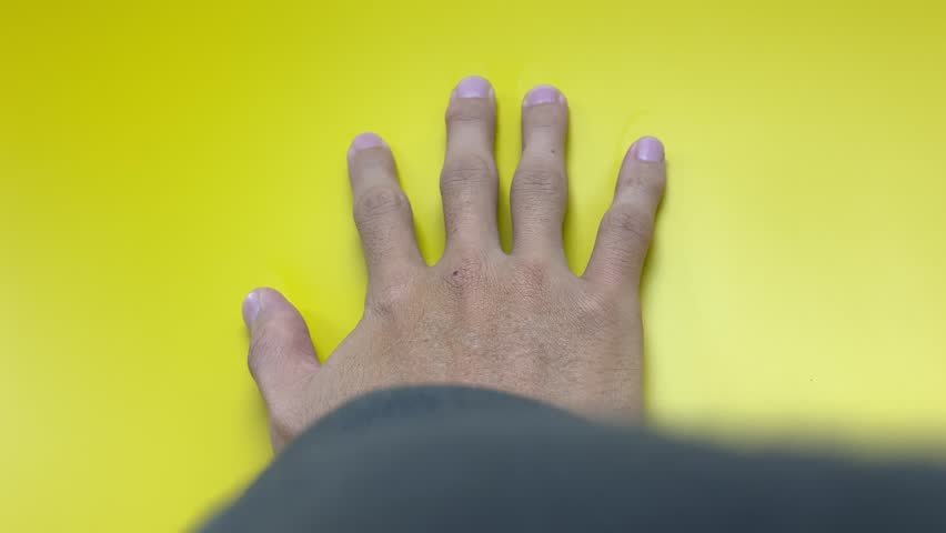 Male right hand palm touching on yellow wall and sliding down slowly 