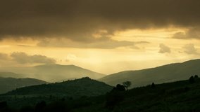 Timelapse mountains. Golden orange cloudy sunset falls on tops of mountains and floods everything around with fog, like tsunami wave. Fantasy amazing nature. Tsunami from clouds. Weather gray sky