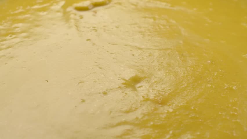 Super close-up of the ladle taking the pumpkin soup puree from the pan in slow motion. High quality FullHD footage