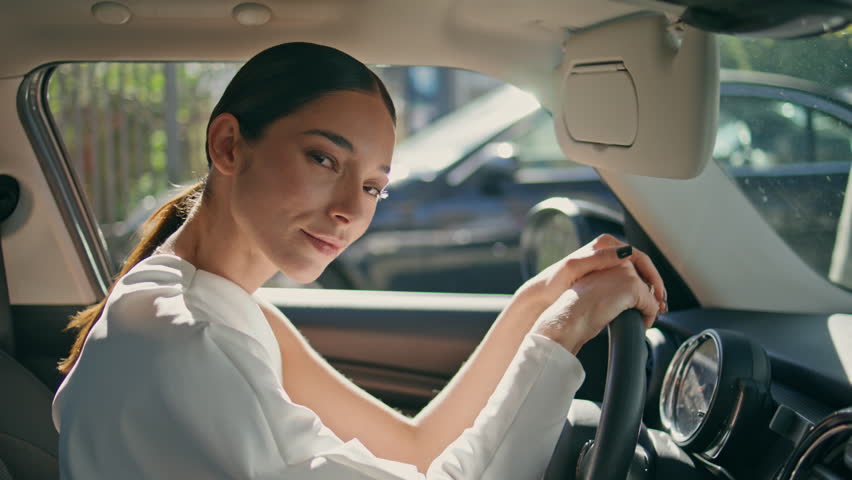 Chic model posing car holding hands on wheel close up. Gorgeous business woman brunette looking camera sitting in luxurious automobile. Elegant girl driver in stylish white suit enjoying vip vehicle. Royalty-Free Stock Footage #1108523887