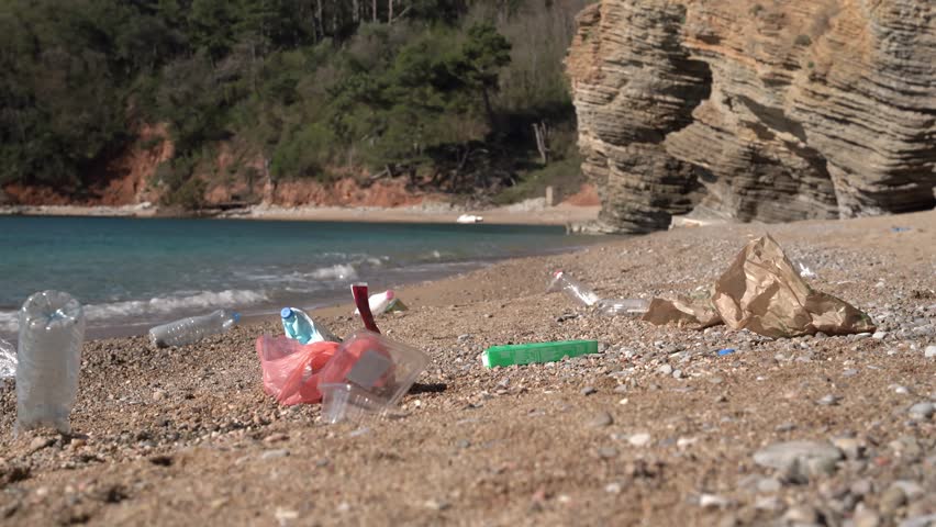 Picturesque beach with beautiful nature, garbage dump of plastic bottle, bag, paper is lying around. Environmental pollution. Vacationers left picnic waste trash by sea. Ecology, the danger of mankind
