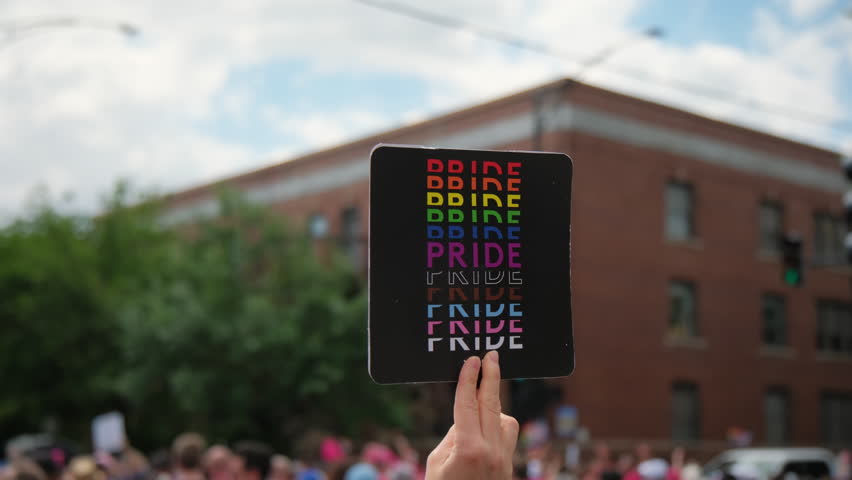 Hand hold Pride flyer and people at pride parade on pride parade