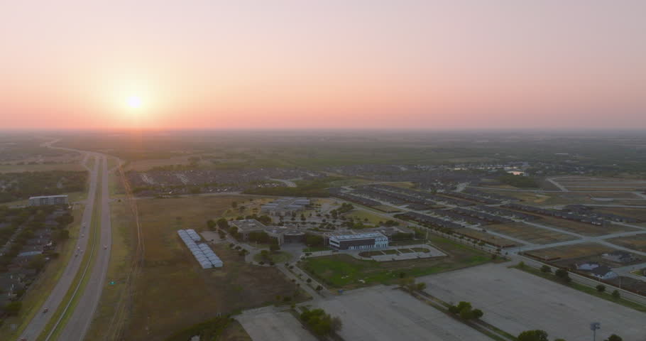 4K aerial drone high altitude view of cars driving on a highway near neighborhoods and a school with the camera facing the dramatic sunset on a hazy evening showing pollution and climate change. | Shutterstock HD Video #1108531209