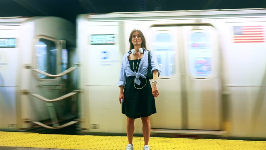 Portrait of caucasian woman at underground train station. Young woman, female passenger looking at camera, portrait shot. Charming woman smiling at station, waiting for train.