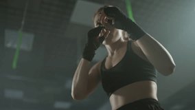 Woman fighter trains his punches and looks at the camera, training in the boxing gym, trains a series of punches fast, front view. - Powered by Shutterstock - Get 15% off with code: PIKWIZARD15