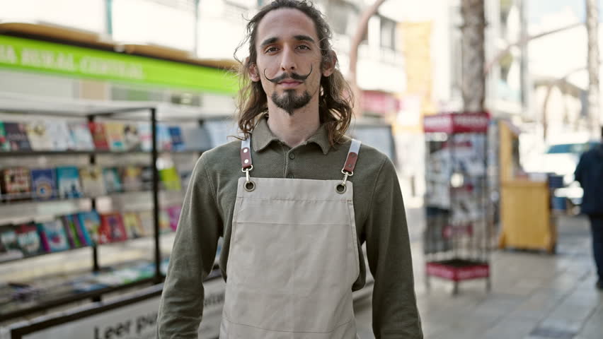 Young hispanic man waiter smiling confident standing with arms crossed gesture at coffee shop terrace
