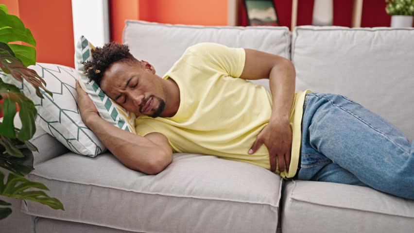 African american man suffering for stomach ache lying on sofa at home Royalty-Free Stock Footage #1108537975