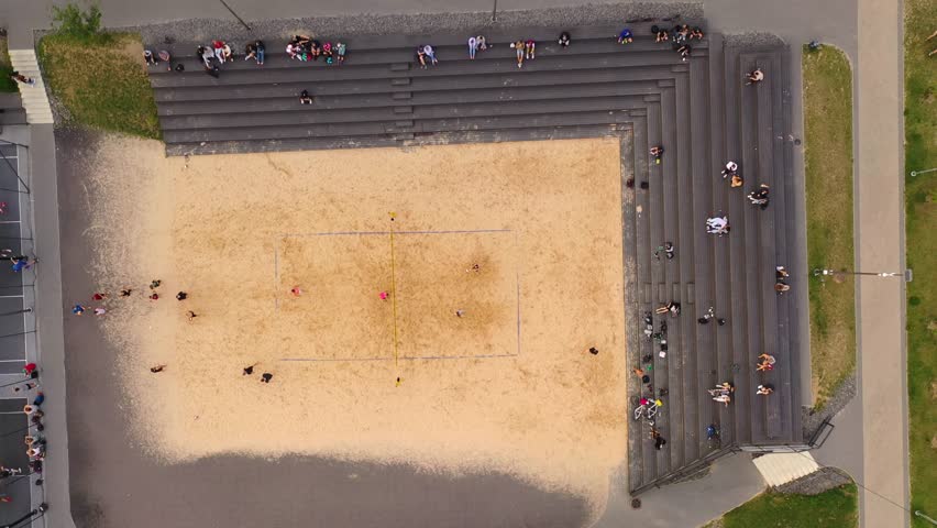 Drone footage of volleyball court and people playing volleyball during summer day.