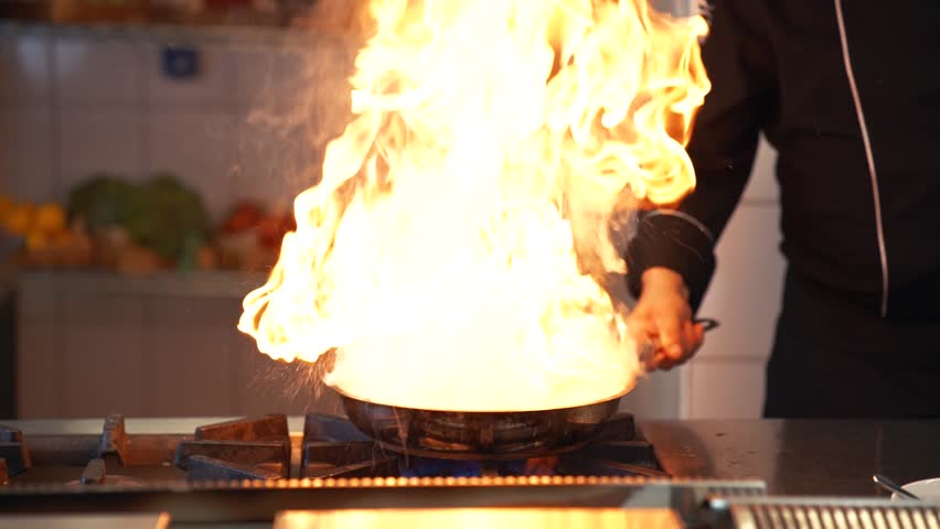 Professional chef is cooking in a frying pan in flames. Royalty-Free Stock Footage #1108541485