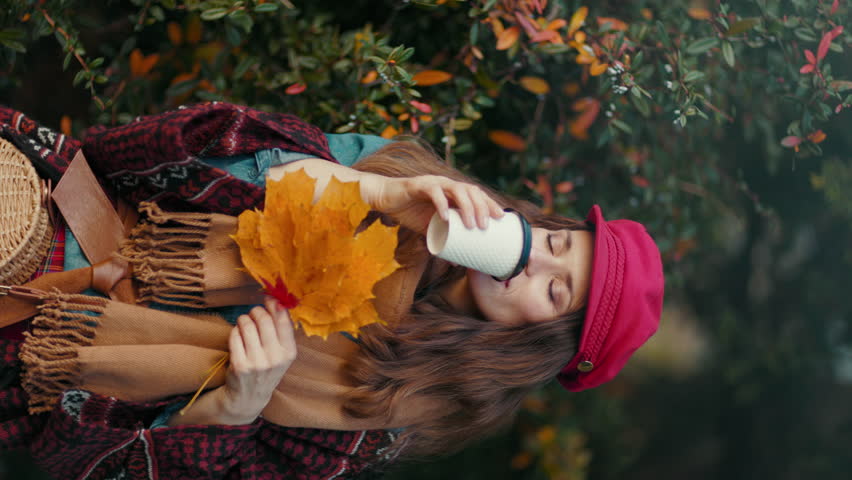 Hello autumn. happy elegant woman in red hat with autumn leafs, scarf, bag and coffee in the city park. Royalty-Free Stock Footage #1108544283