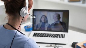 online medicine, a female doctor using a microphone and headphones consults elderly patients via video conference during medical appointment while sitting in office