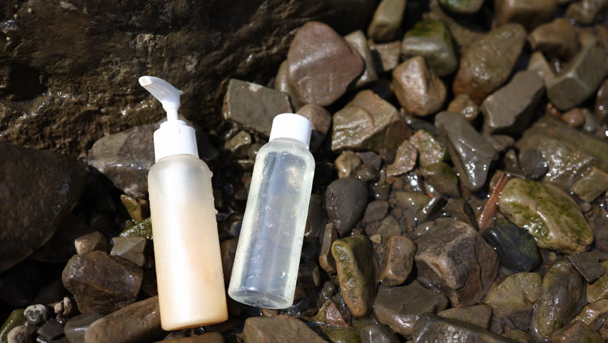 Two bottles of a container with shower gel cosmetics lie on wet stones. makeup. September | Shutterstock HD Video #1108547465