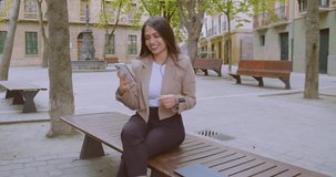 latin woman smiling while looking her phone in the street