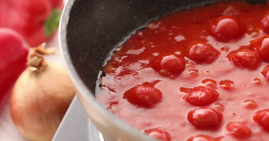 Tomato sauce boiling in a pan with bubbles and steam, being stirred with a spoon. Cooking bolognese sauce. Food preparation in the kitchen. A series of footage to visualize the recipe.