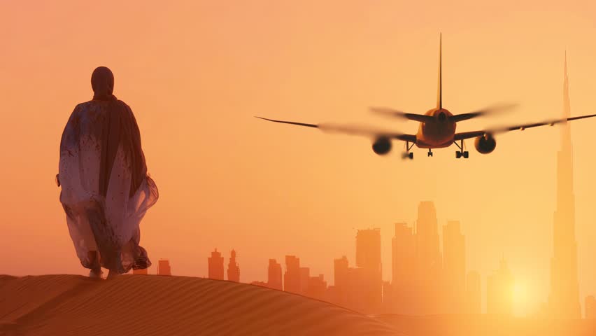 Islamic woman stands in the desert and looks on the landing plane at the sunset with Dubai city silhouette. Travel concept video