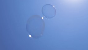 Lot of Transparent Shining Soap Bubbles with Sun Glare fly in Blue Sky. Clear blue background. Sun glare, reflection. Colored bubbles are moving fast. Bottom view. Selective focus. Nature background. - Powered by Shutterstock - Get 15% off with code: PIKWIZARD15