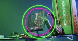 Animation of neon circles over video game computer equipment. Global video game, digital interface, data processing and connections concept digitally generated video.