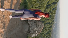 Vertical Video, Slim Athletic Woman in Sports Overalls Runs Edge on Top Mountain on Background Beautiful Natural Landscape. Happy Girl on Top Mountain Enjoys Feeling Victory and Success. Slow Motion.