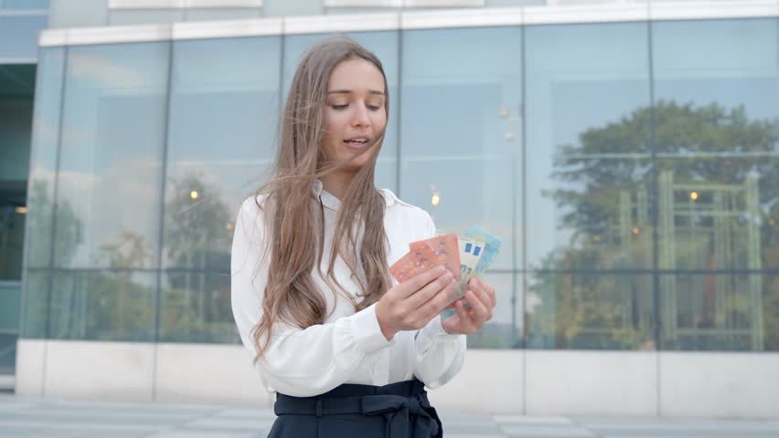 Business woman counts euro's outside of modern office building