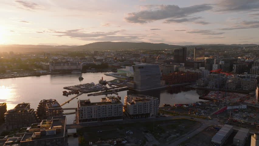 Aerial shot of modern town development around bay in city at sunset. Multistorey apartment buildings, Munch museum and Oslo Opera House. Oslo, Norway Royalty-Free Stock Footage #1108571375