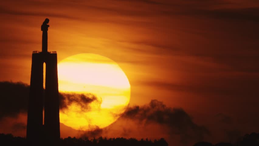 Portuguese statue of Jesus Christ at a bright orange sunset