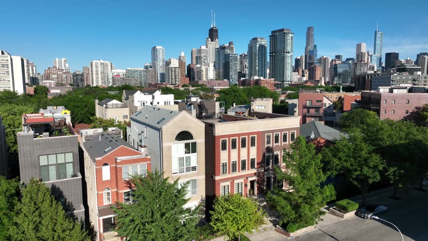New housing near downtown Chicago. Aerial shot of modern condos and apartments with Chicago, Illinois skyline in background. Lush trees in neighborhood in summer.
