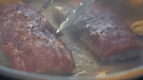 Chef cooks delicious meat in a pan with smoke in slow motion
