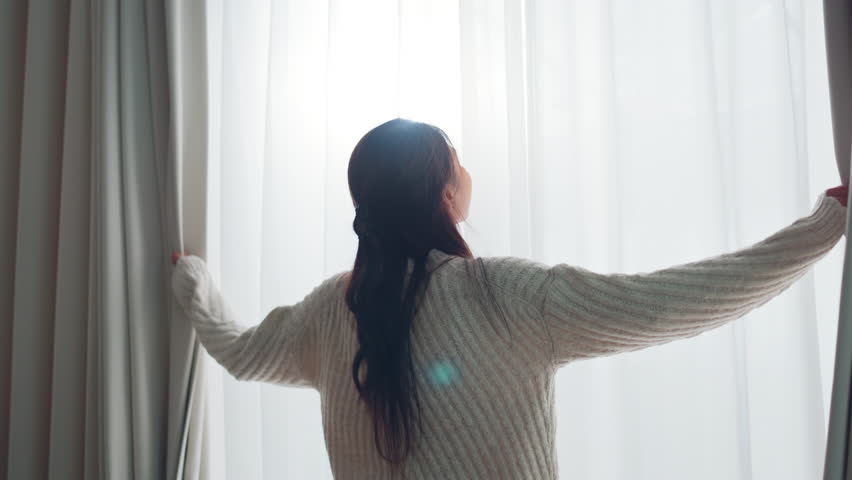 Smiling Asian woman opening curtains at morning, Hands pulling window curtain, slow motion