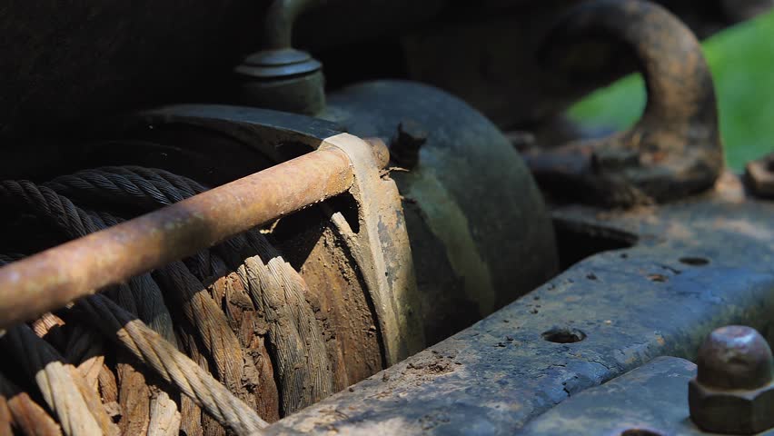 Car winch on SUV bumper with coiled steel cable. Old dirty winch with rusty cable on offroad vehicle. The winch is off-road equipment