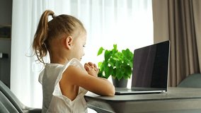 Little girl does finger gymnastics online on the laptop home. Distance learning concept. High quality 4k footage