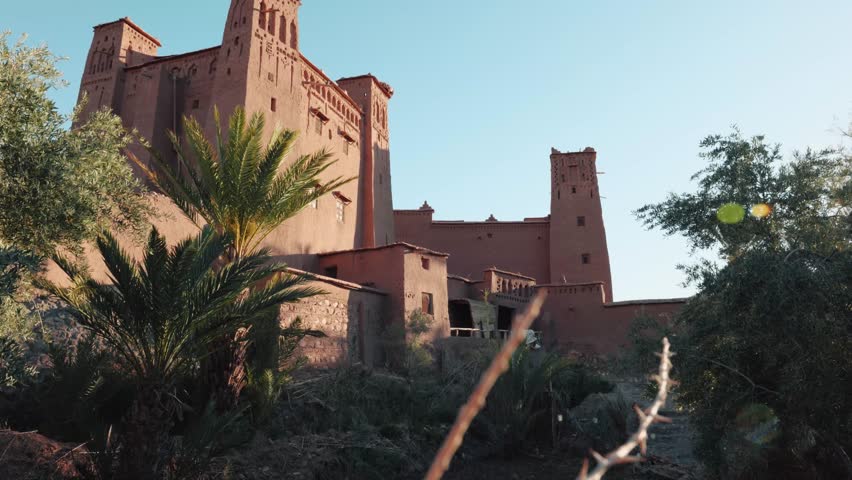 Wide view of traditional mud buildings and palm trees in Ait Ben Haddou, Morocco.