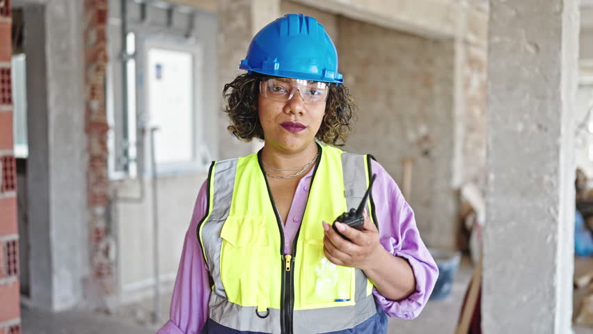 Young beautiful latin woman builder holding walkie talkie doing thumb up gesture at construction site Royalty-Free Stock Footage #1108586217