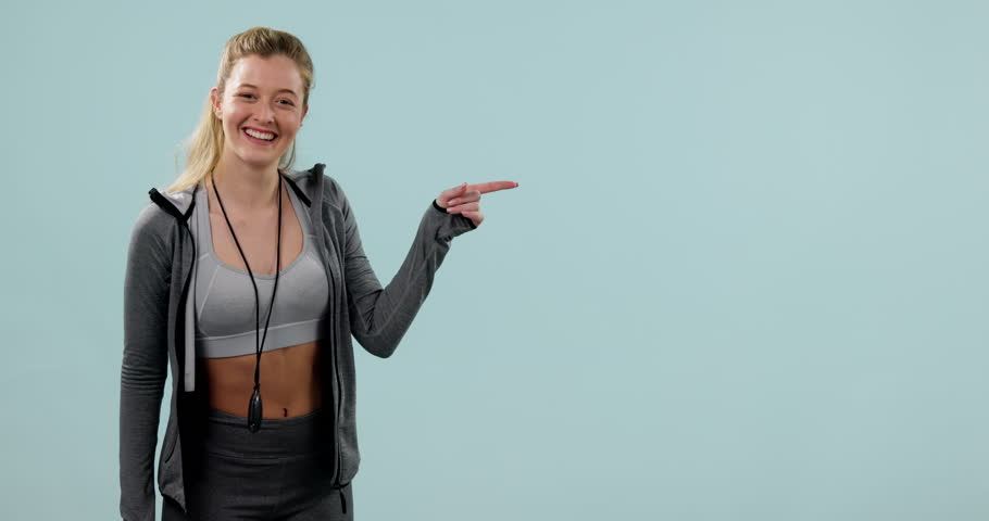 Fitness, face smile and woman pointing at mockup space in studio isolated on a blue background. Portrait, happy athlete advertising and marketing workout of coach or promotion of personal trainer