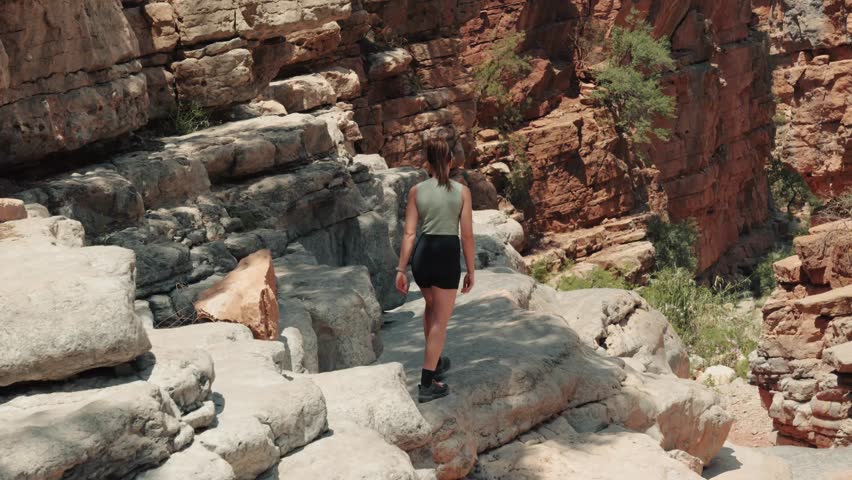 Close view of young caucasian woman walking up to and edge of a cliff in Paradise Valley, Agadir, Morocco.
