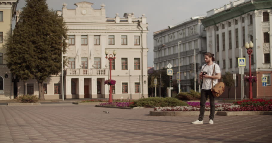 Male photographer taking shots on city square