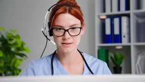 online medicine, young charming female doctor with a headset consults a patient via video conference on laptop in a hospital office