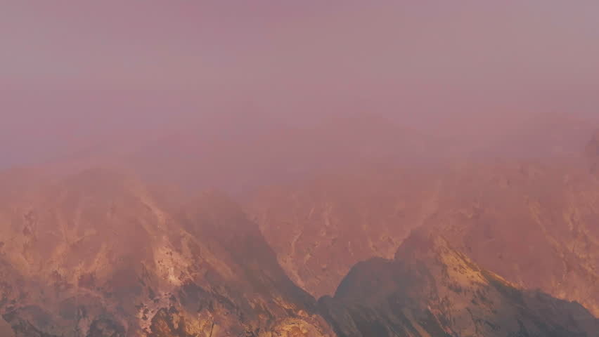 Drone rising above a ridge on the rocky mountains. Flight over incredible epic mountain landscape. Aerial 4K