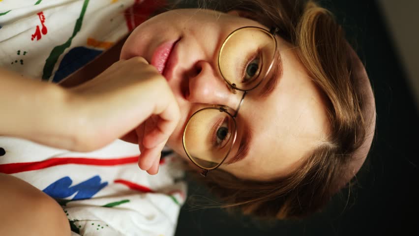 Beautiful girl in glasses looks at the camera and hugs herself. woman at home in a dressing gown. vertical video | Shutterstock HD Video #1108600897