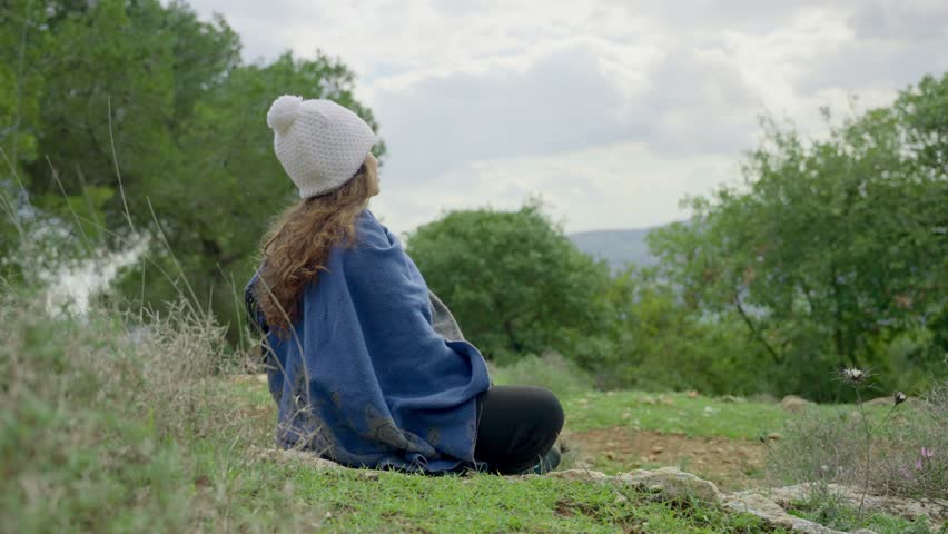 Hippie or New Age young woman enjoying nature while doing meditation poses. Carefree free spirit female dressed in hippie bohemian bo-ho clothes in spiritual ceremony thanking mother nature and sun