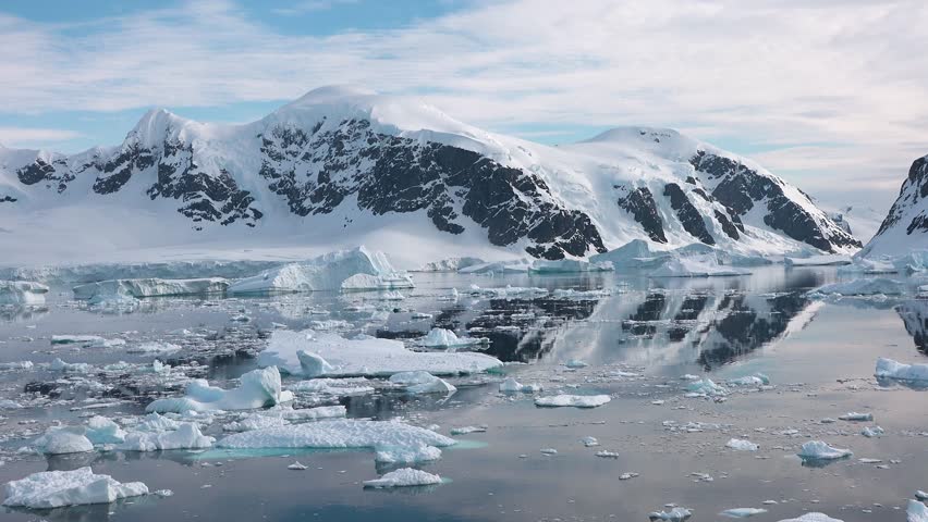 Antarctica. Icebergs. Global warming and climate change. Beautiful nature. Landscape of snowy mountains and icy shores. Beautiful blue iceberg with mirror reflection floats in open ocean. Glaciers