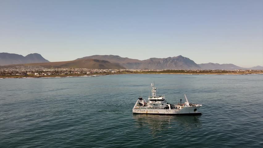 Marine research vessel drifting off the coast with mountains in the back on a calm day Royalty-Free Stock Footage #1108604835