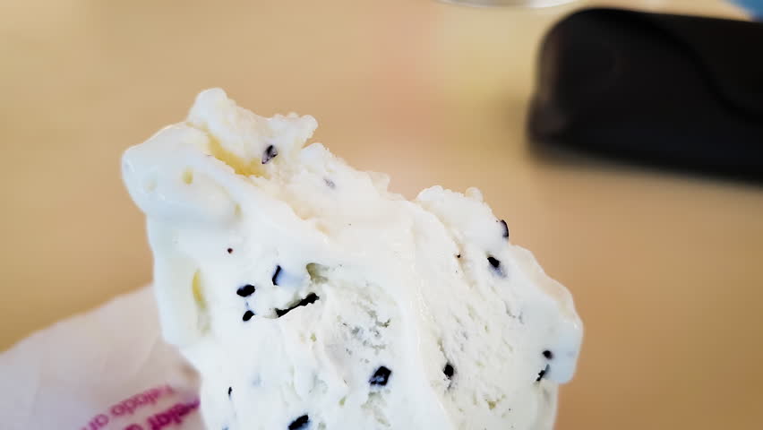 Closeup shot of a hand taking a spoonful of the soft stracciatella italina ice cream