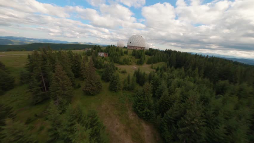FPV, Abandoned radar station Pamir in Carpathian mountains, research station on top of the mountain in the Carpathians in Ukraine. large white balloons designs in the mountains among the fir trees