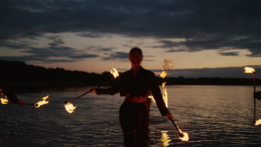 Beautiful Women Dancing With Fire, Professional Fire Performance On Beach Of Lake After Sunset