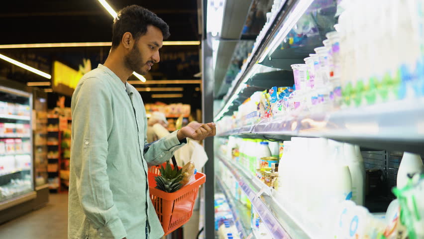 Side view of handsome indian man buying milk. A man shopping dairy product in grocery store