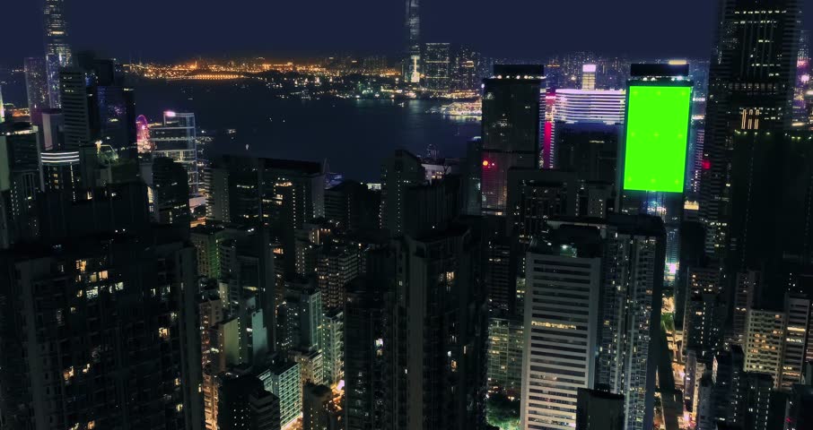 AERIAL. Top view of skyscrapers and green screen build board with tracking point. Bird view of modern city at night streets.