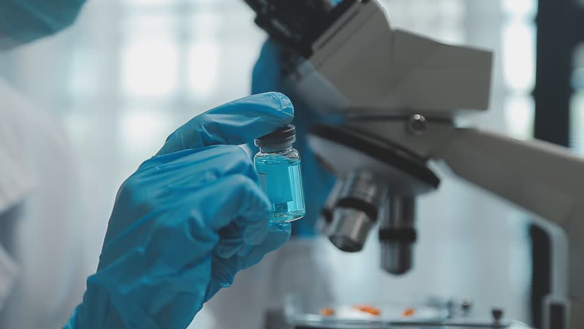 Health care researchers working in life science laboratory. Young female research scientist and senior male supervisor preparing and analyzing microscope slides in research lab. Royalty-Free Stock Footage #1108623645