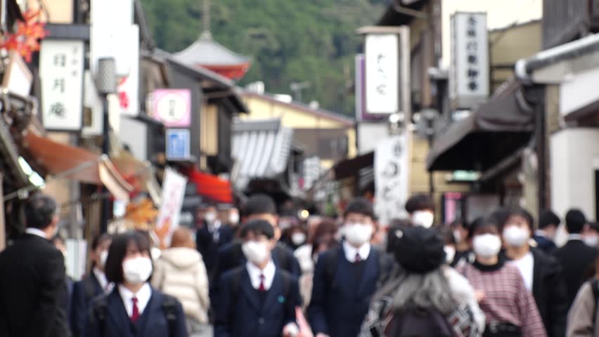 KYOTO, JAPAN - DEC 2021 : Back shot and crowd of people with mask to protect from Coronavirus (Covid-19). Many tourists around Kiyomizudera (Kiyomizu Temple) in autumn leaves season. Slow motion shot.